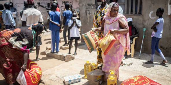 Une femme reçoit des denrées alimentaires, à Dakar, le 28 avril.